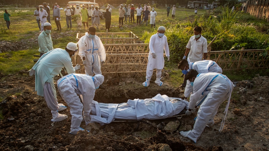 Workers in hazmat gear carry the body of a person who died from COVID-19