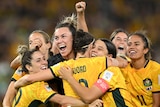 The Matildas hug, cheer and fist pump the air as they celebrate on the field.