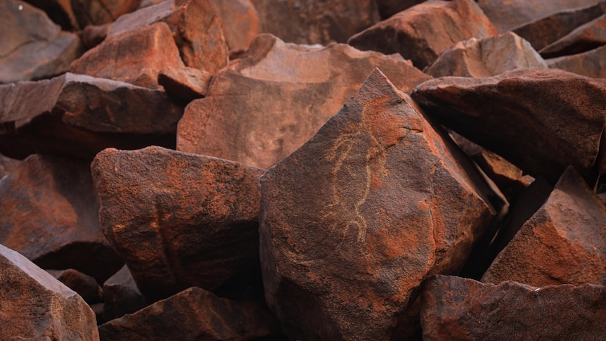 Rock art depicting a lizard on a large red rock.