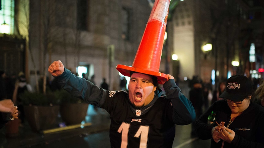 A Philadelphia Eagles fan marches with a cone on his head, yelling and celebrating