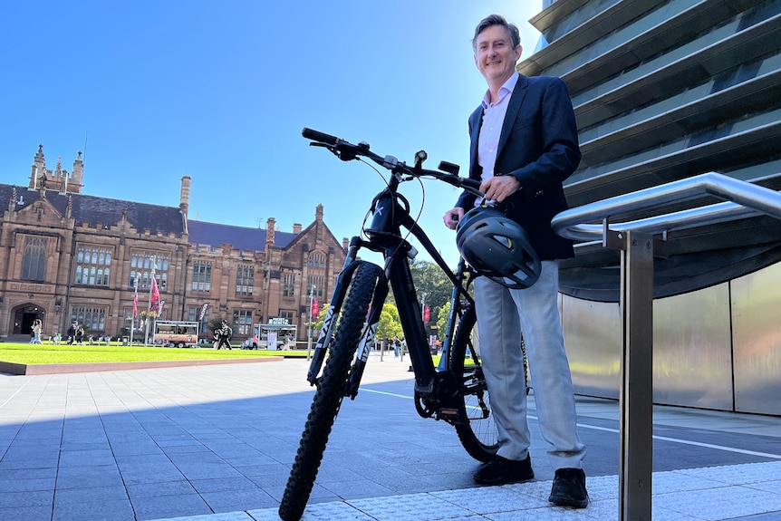 Professor Luke Nottage stands next to a bicycle.
