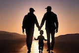 A Same sex family with a child walk at sunset in a silhouette image.