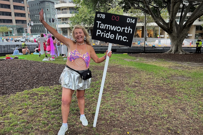A middle aged woman holds a sign at Mardi Gras in Sydney. 