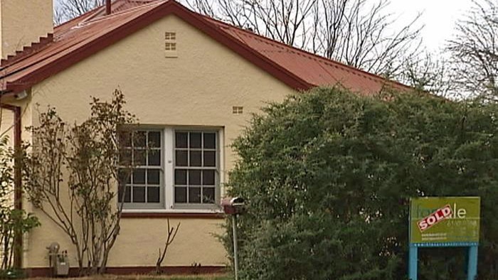 Older style Canberra House with real estate sign saying sold.