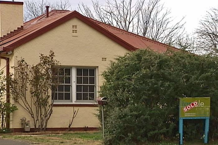 Older style Canberra House with real estate sign saying sold.