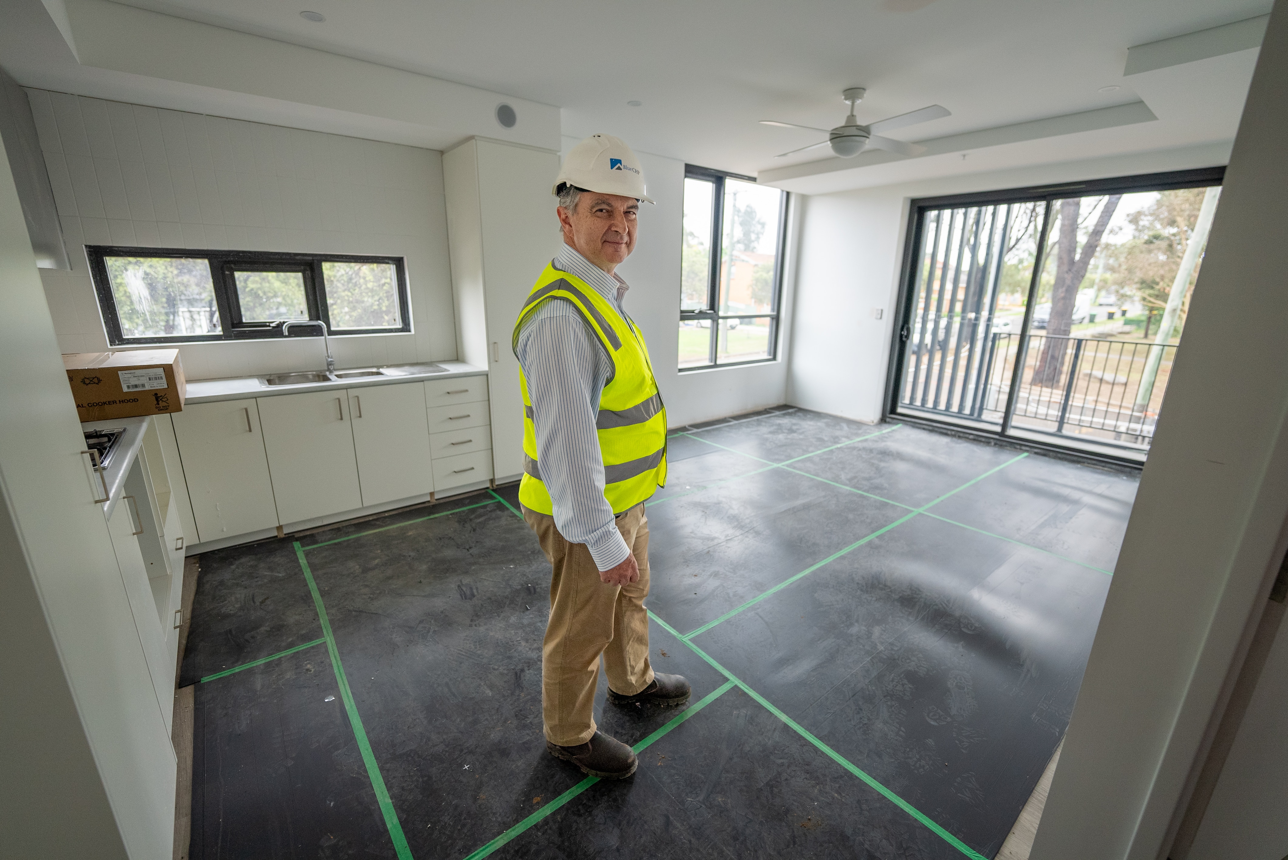 Hombre con chaleco de alta visibilidad y sombrero de ciervo parado en una cocina sin terminar.