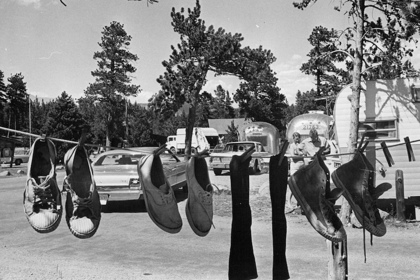 A black and white photo of washed sneakers hanging on a shoe line.