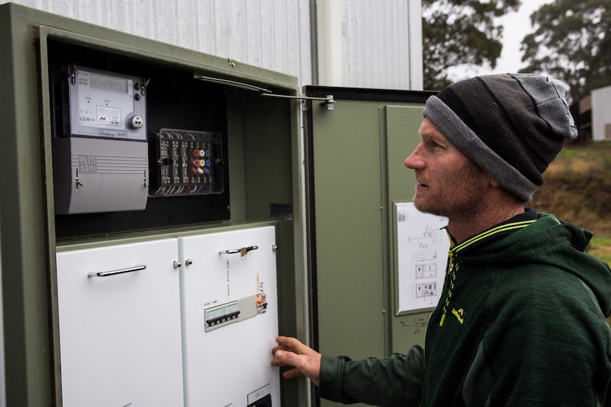 A man looks at at power meter box.