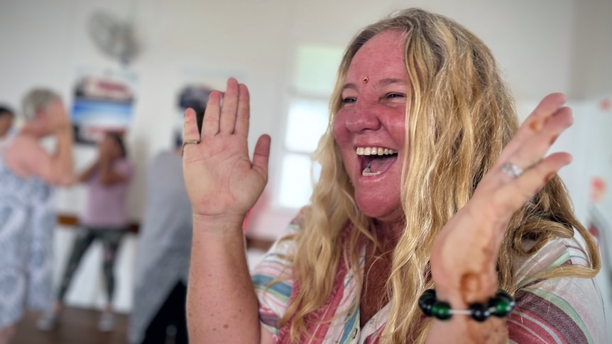 Woman claps hand with mouth open in joyous laughter