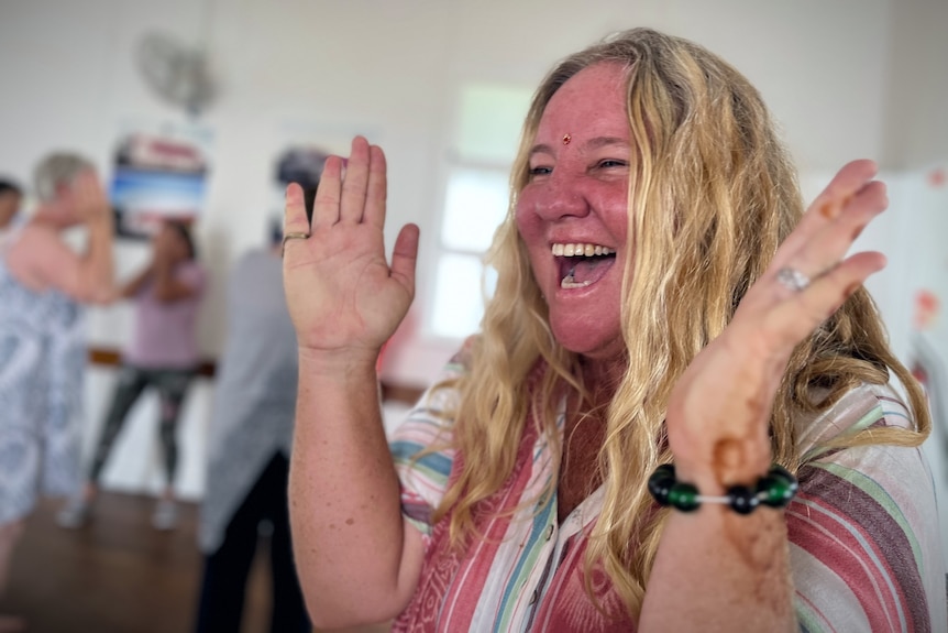 Woman claps hand with mouth open in joyous laughter