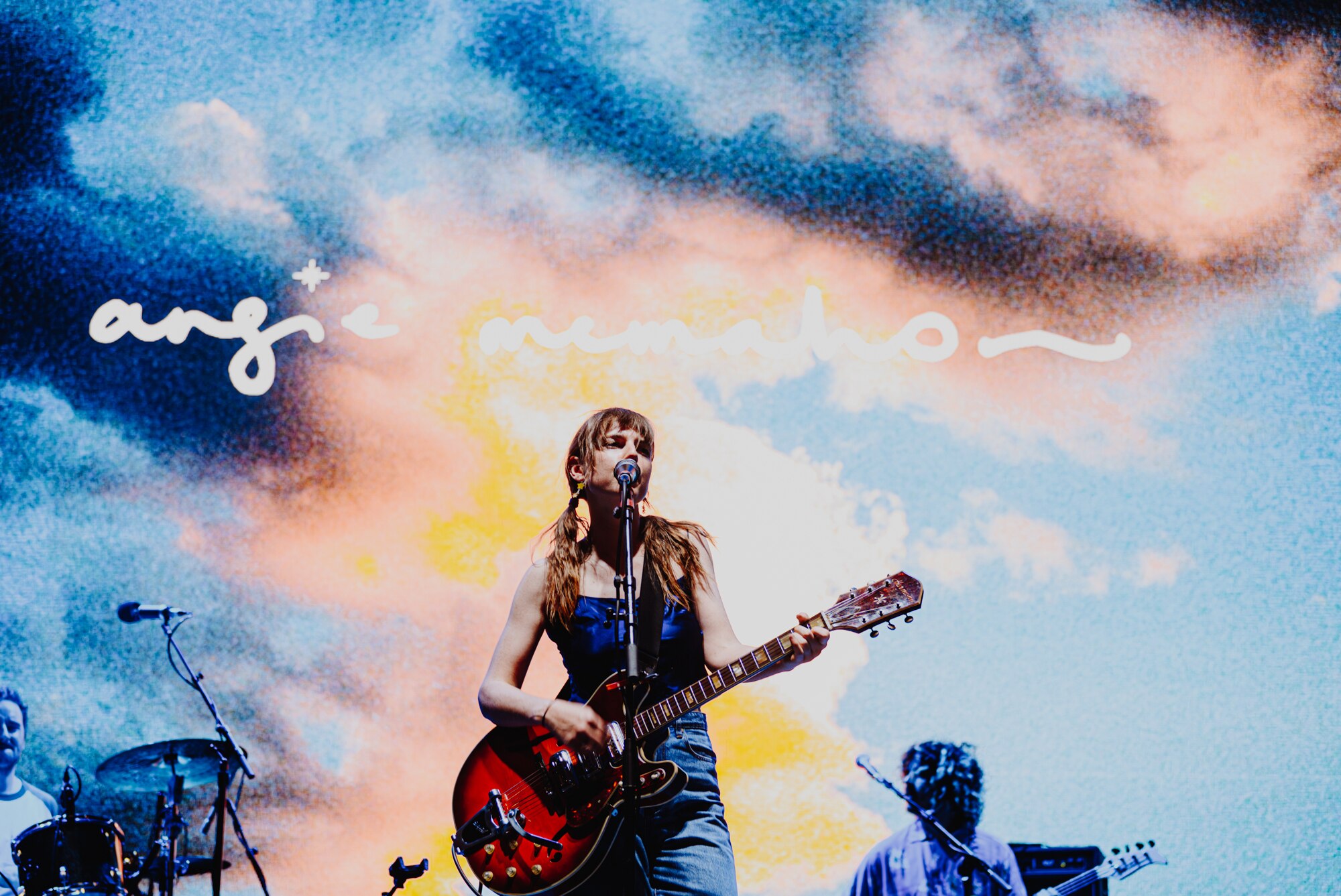 Angie McMahon performs live at Laneway Festival 2024 with a red guitar and under blue lighting