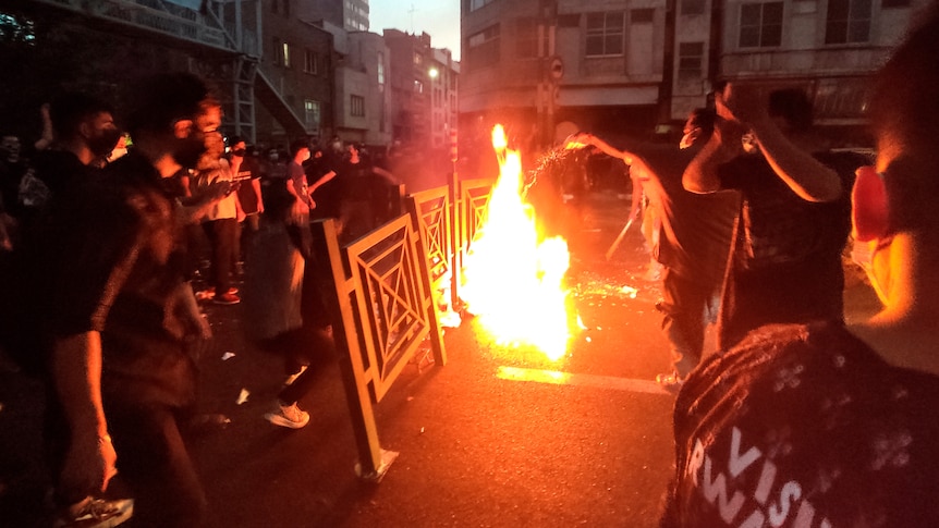 Protesters make fire and block the street during a protest over the death of a woman who was detained by the morality police.