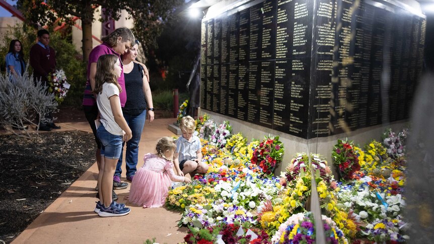 A woman with her four children laying a floral wreath in front of a memorial for mining industry workers.  