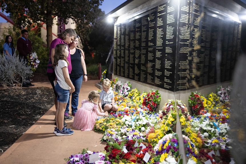A woman with her four children laying a floral wreath in front of a memorial for mining industry workers.  