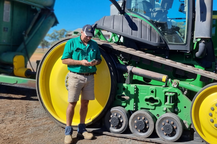Man with phone in front of tractor