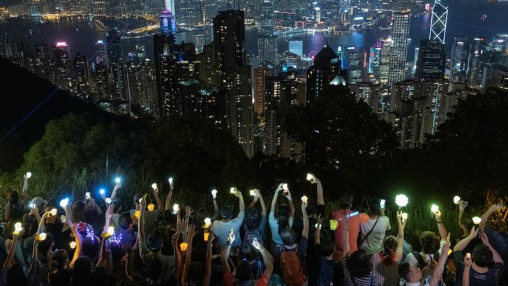 Demonstrators holding their phones are seen against the city lights on new years eve.