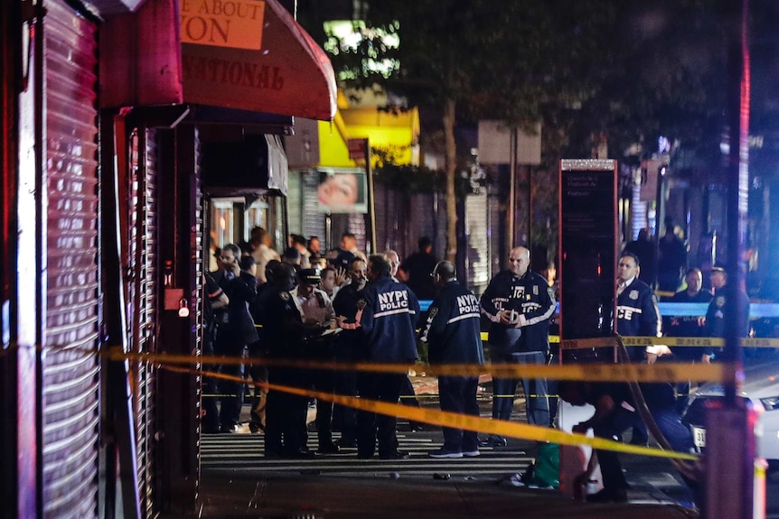 A group of NYPD officers in uniform gather behind police tape.