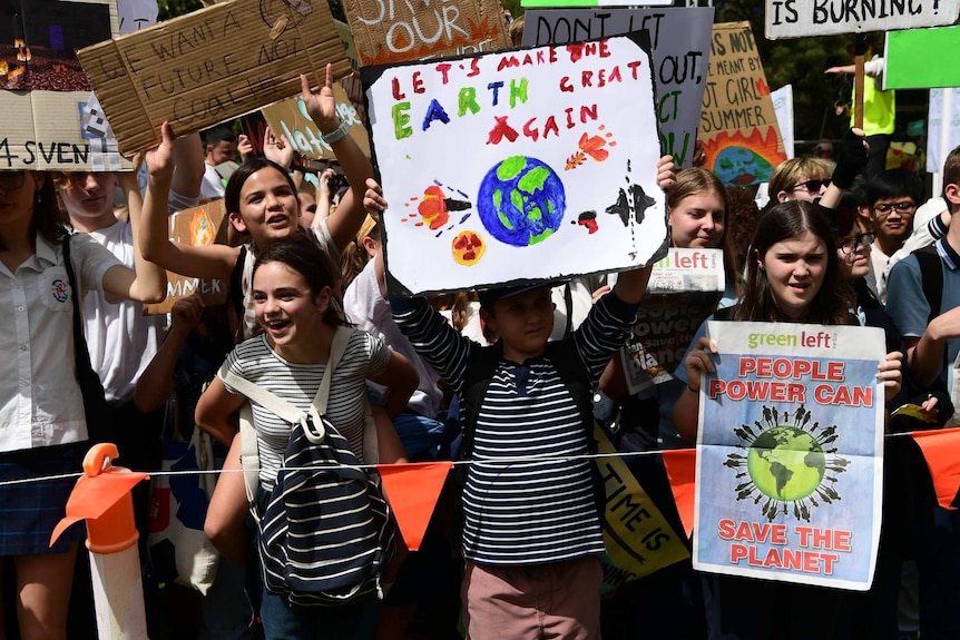 Primary school aged children hold cardboard posters and placards