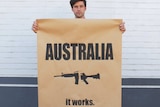 Peter Drew holding his gun laws campaign poster