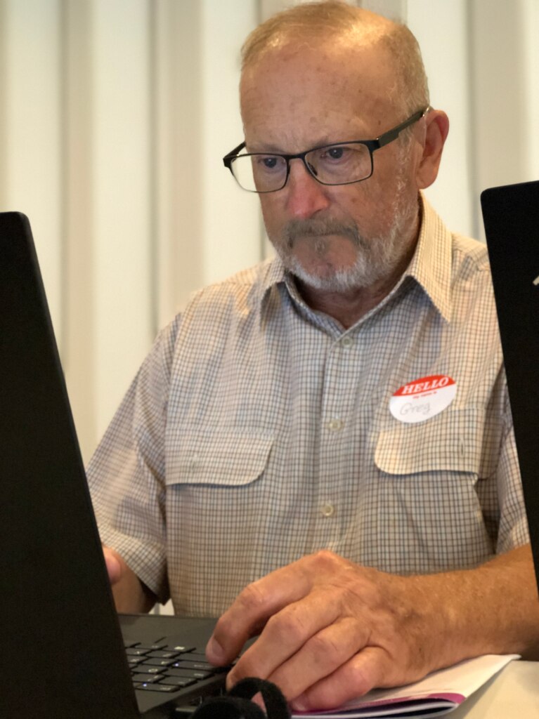 Older man sitting in front of a computer screen looking determined.