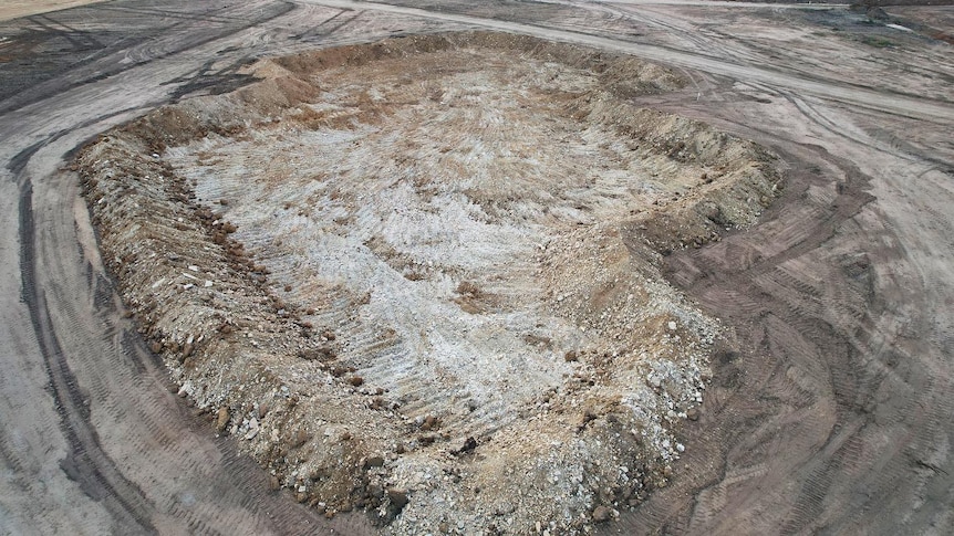 an aerial photo shows a mine site excavation area, with rocks around the perimeter