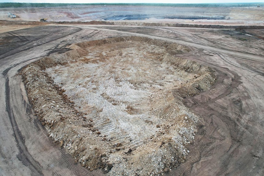 an aerial photo shows a mine site excavation area, with rocks around the perimeter