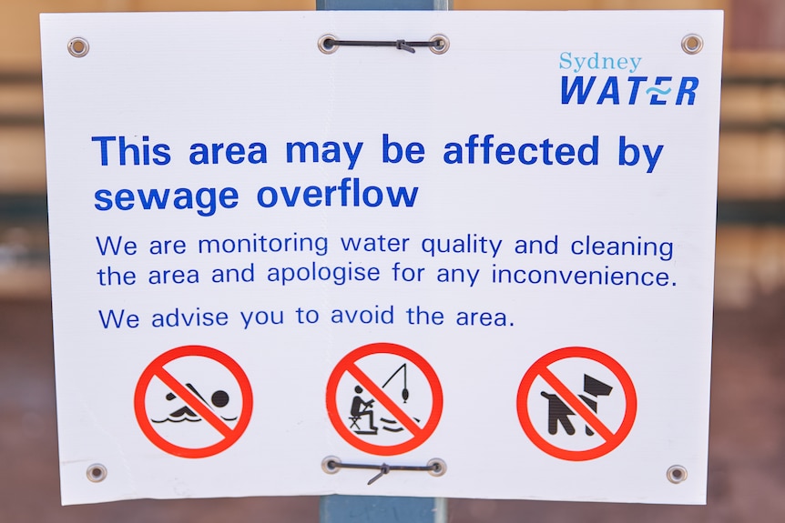 A sign attached to a fence saying this area may be affected by sewage overflow