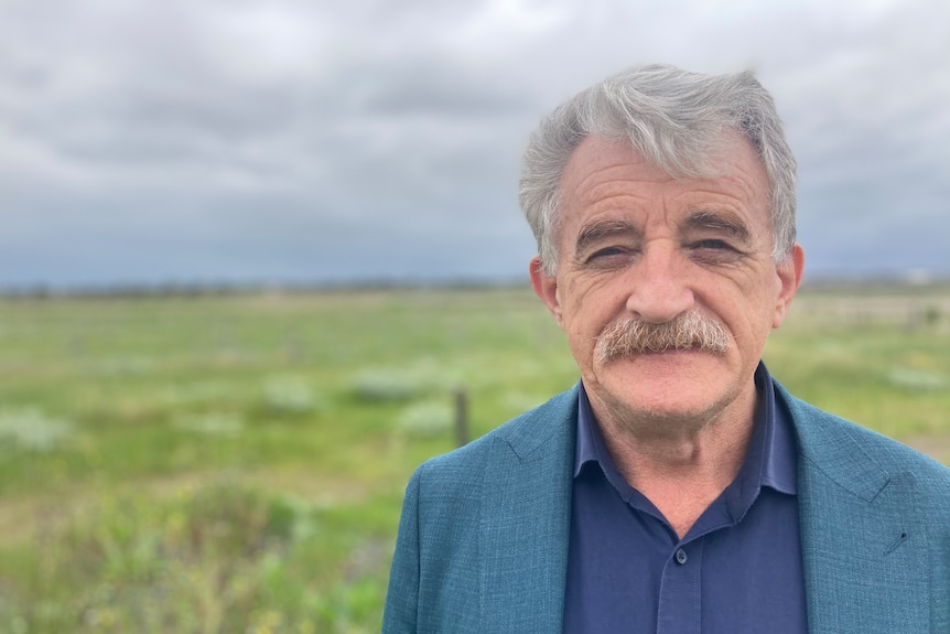 A man in a suit standing in front of a field