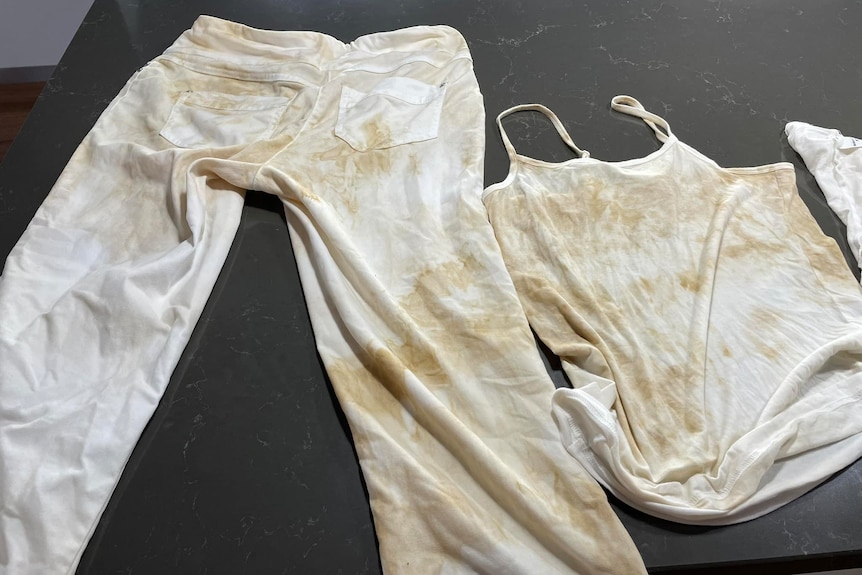 white clothes stained heavily with brown dirt lay spread out on a counter top