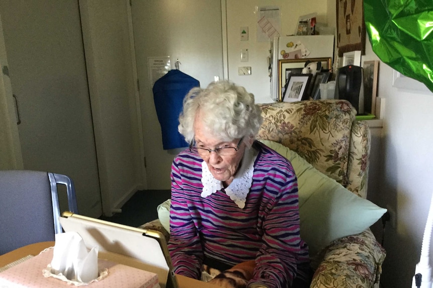 An elderly woman communicating with family using an iPad during coronavirus quarantine.