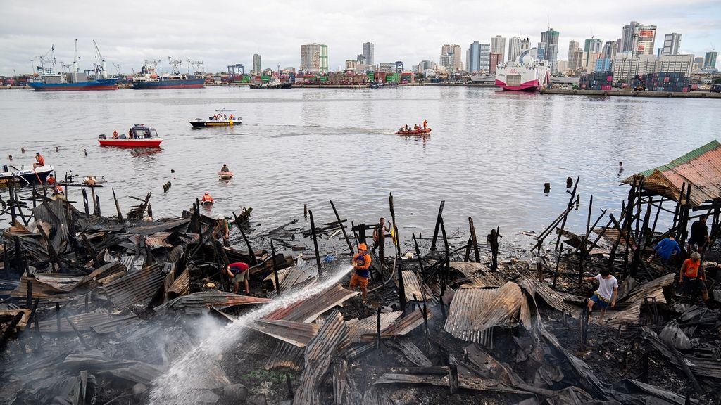 A man hoses the burnt remains of a shanty town on the Manila waterfront. 