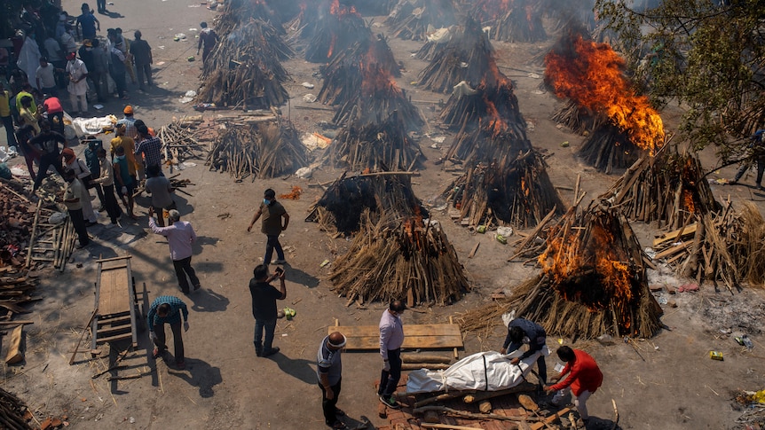 Multiple funeral pyres of victims of COVID-19 burn at a ground that has been converted into a crematorium for mass cremation.