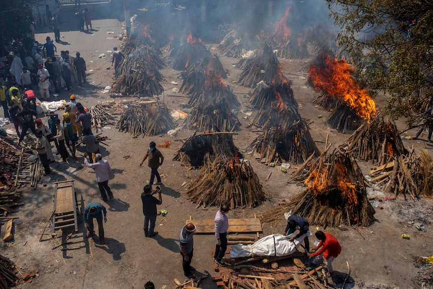 Multiple funeral pyres of victims of COVID-19 burn at a ground that has been converted into a crematorium for mass cremation.