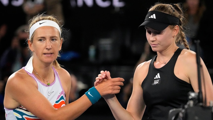 Two players face the camera as they shake hands at the net after their women's tennis match at the Australian Open.