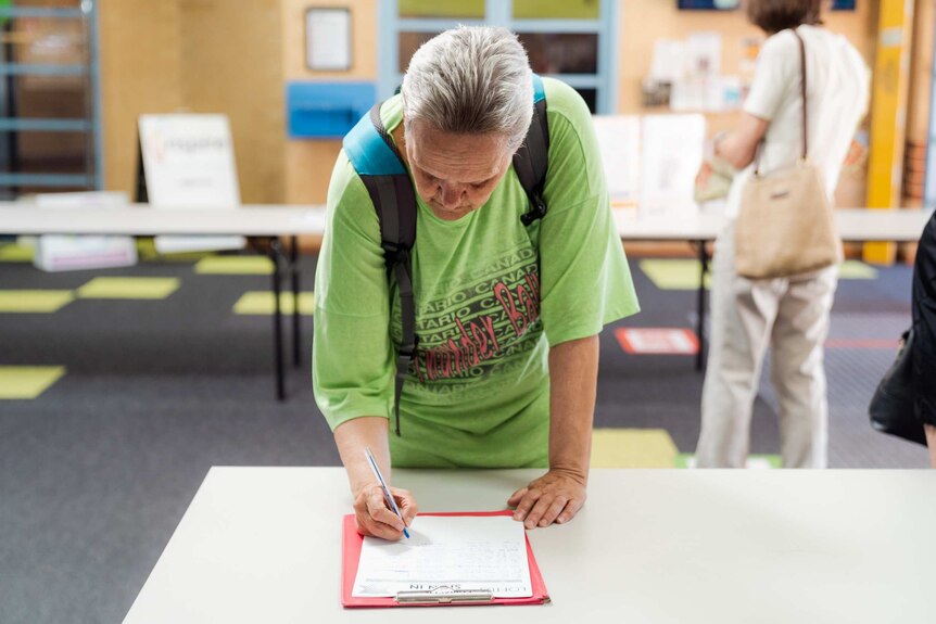 A person signing a contact tracing register.