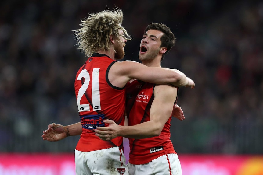 Kyle Langford's mouth is open as he engages in a big hug with Dyson Heppell.