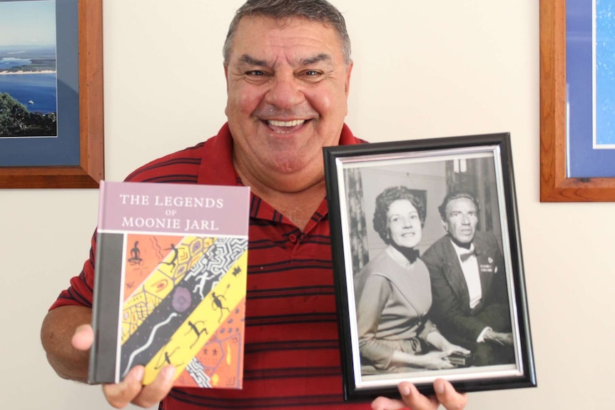 Glen Miller holds a book called The Legends Of Moonie Jarl and a photo of his mother and uncle taken in the 1960s.
