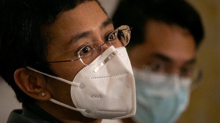 Maria Ressa, wearing a facemask speaking to the media beside former Rappler reporter Reynaldo Santos Jr.