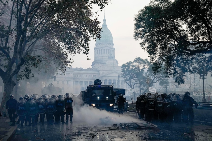 Riot police stand outside a parliament house building during a protest