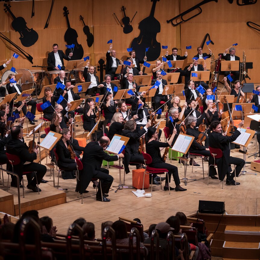An orchestra receiving applause at the end of a performance.
