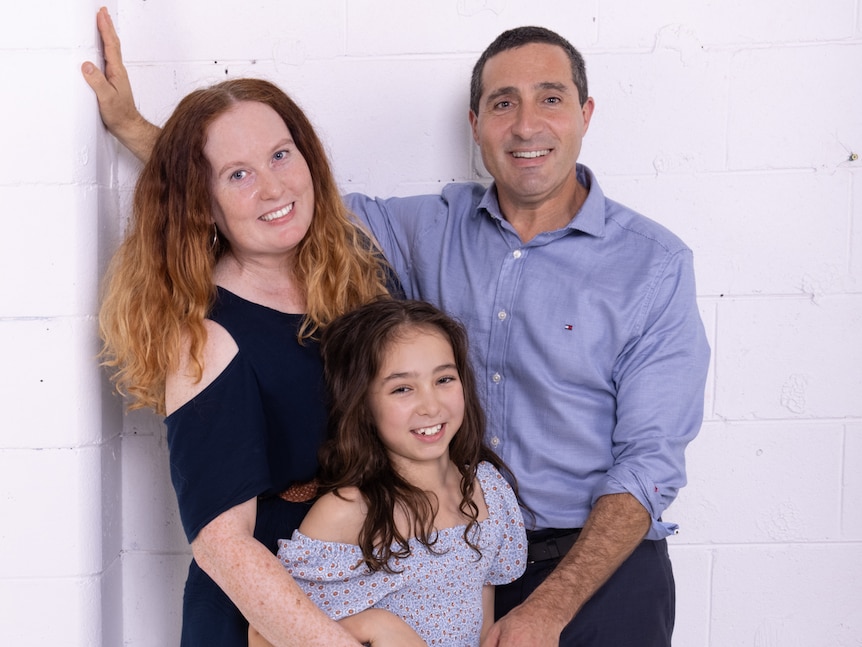 A family smiling standing next to each other