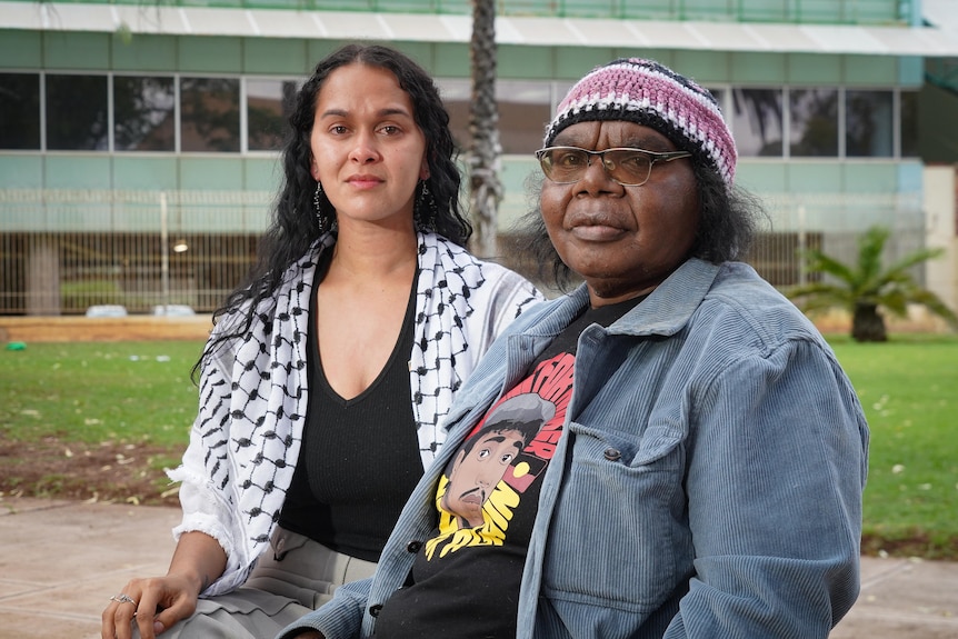 two aboriginal women looking emotional on a park bench