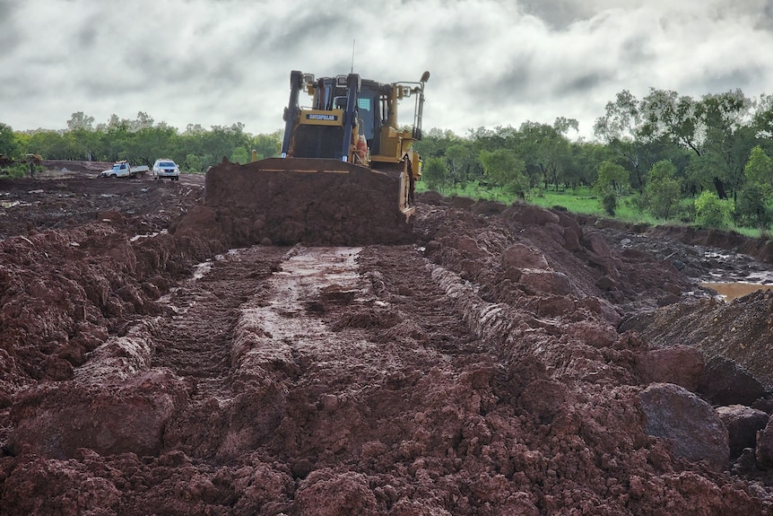 A bulldozer clearing mud and damaged road