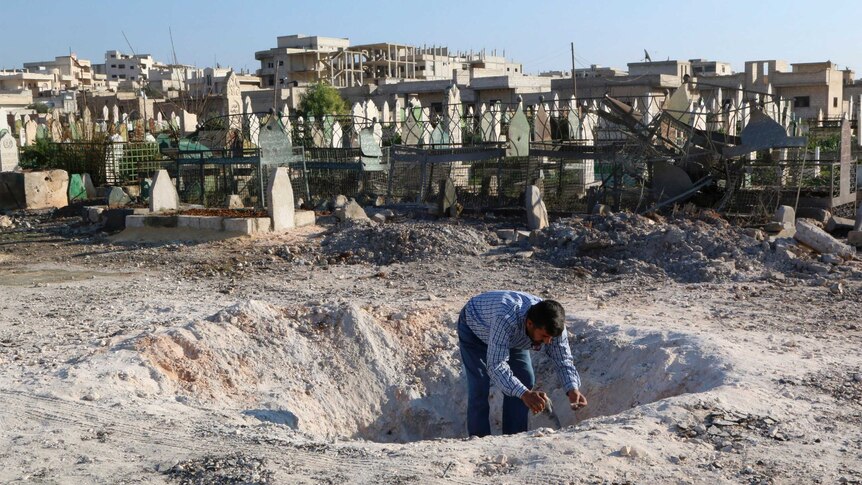A man inspects a hole in the ground after what activists said was an airstrike from forces loyal to Syria's president Bashar Al-Assad in northern Idlib province December 26, 2014.