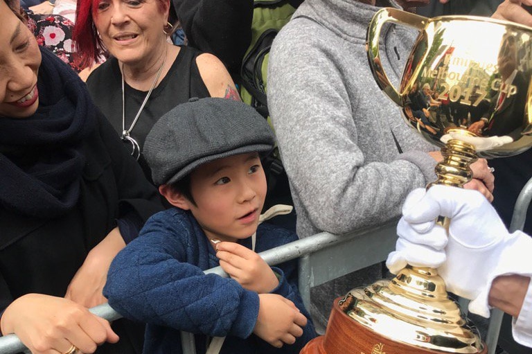 A young boy gets close to the Melbourne Cup at the 2017 Melbourne Cup parade.