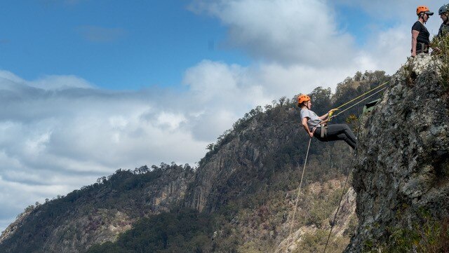 Woman about to abseil over the side of mountain cliff in the Barrington Tops.