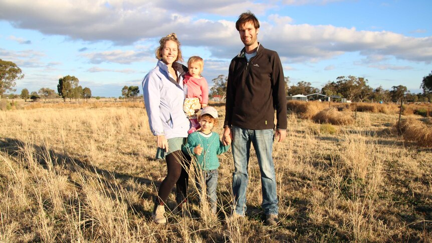 Wide portrait shot of a man, a woman and two children in a paddock in late afternoon sun.