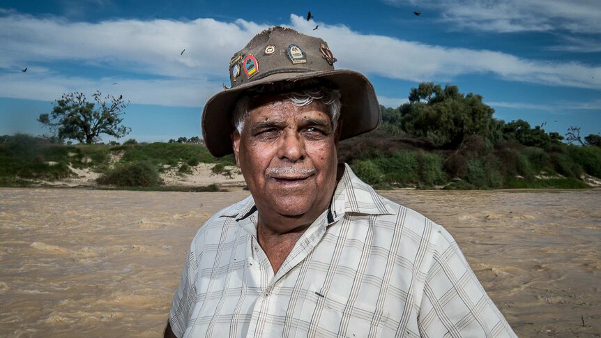 Indigenous ranger Don Rowlands stands on the water's edge.