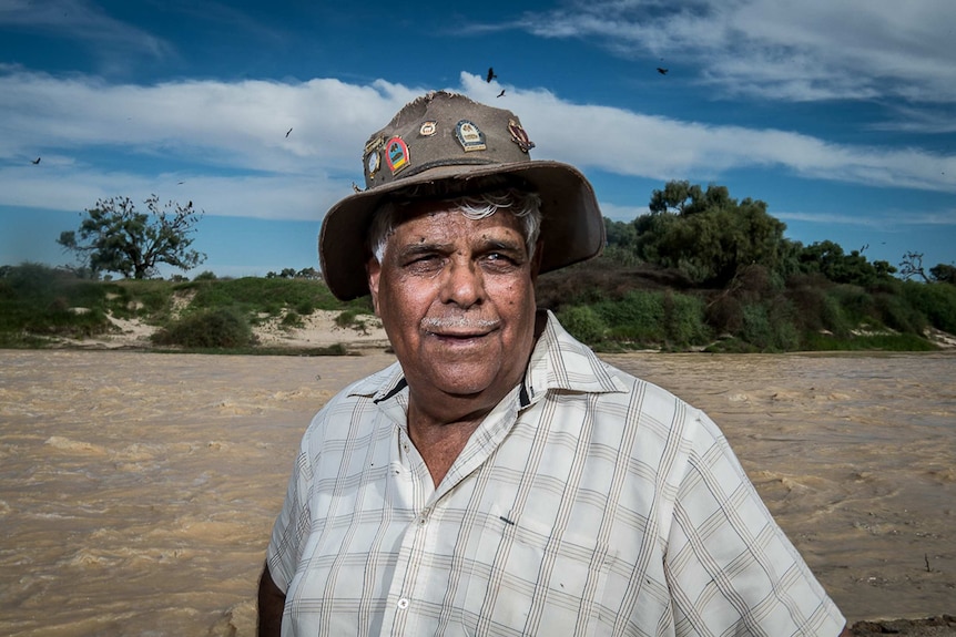 Indigenous ranger Don Rowlands stands on the water's edge.