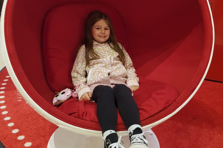 Tiana Djurasovic smiling while sitting in a big red chair